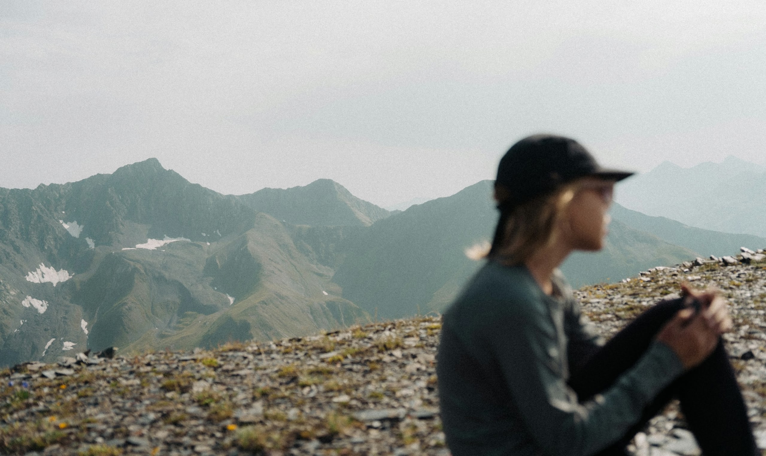 Profile view of women in hat sitting on top of a mountain on a sunny day