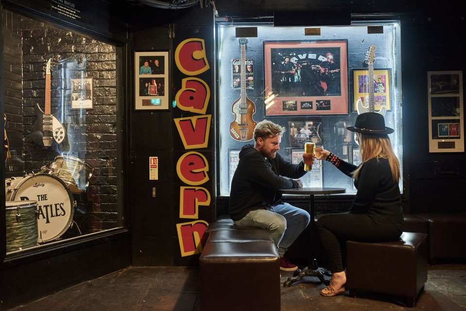 Man and woman toasting with white wine and beer at The Cavern Club, Liverpool, UK.