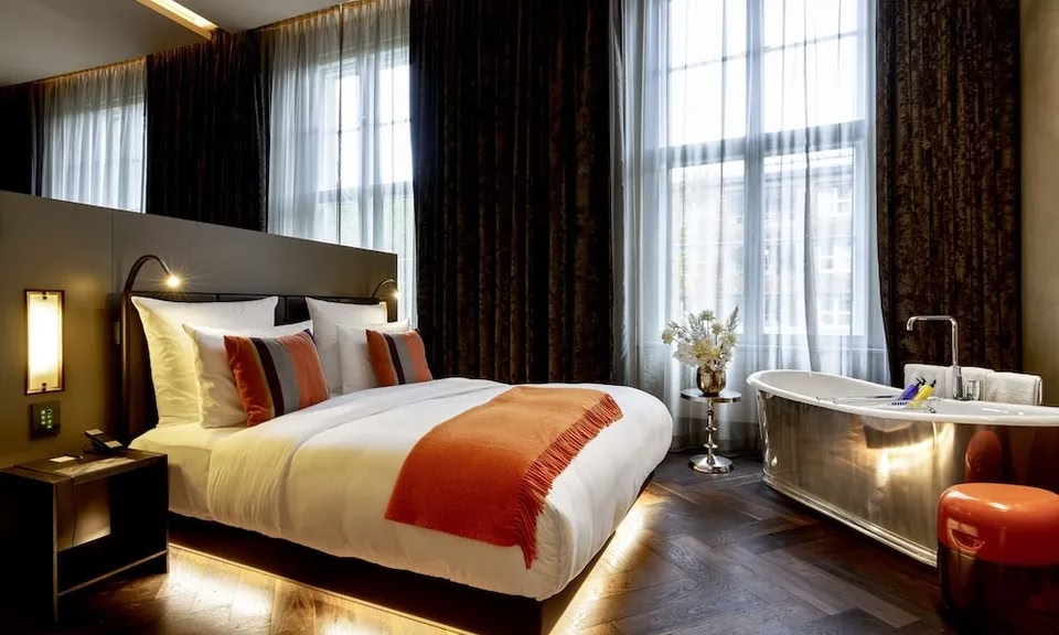 Una suite de hotel con bañera independiente junto a la cama en el hotel boutique SO/ Berlin Das Stue.