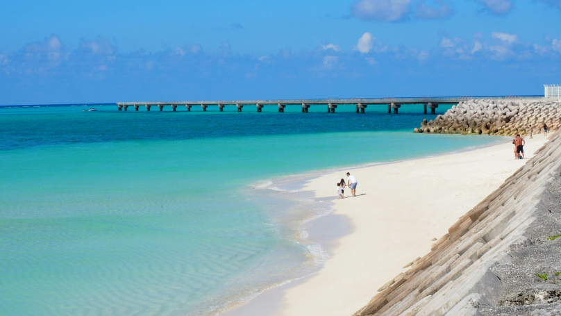 Persone che passeggiano sulla riva del mare in Giappone in una giornata di sole.