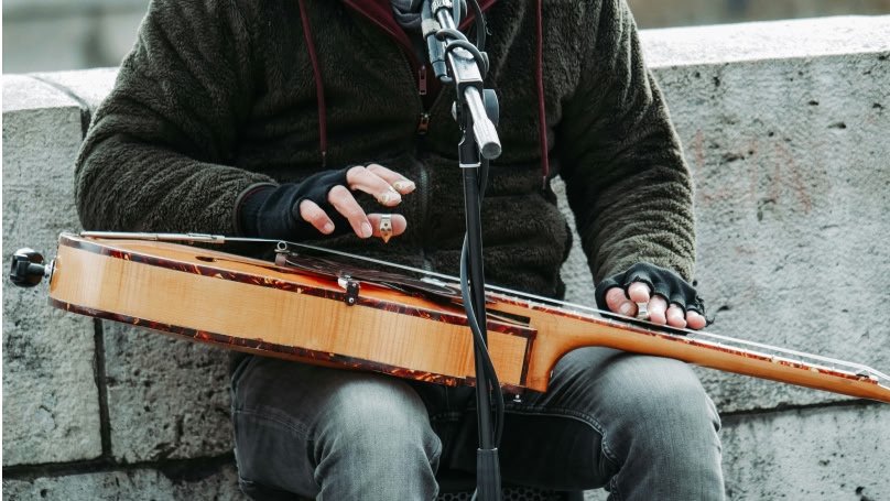un'immagine ravvicinata di un artista di strada che suona una chitarra