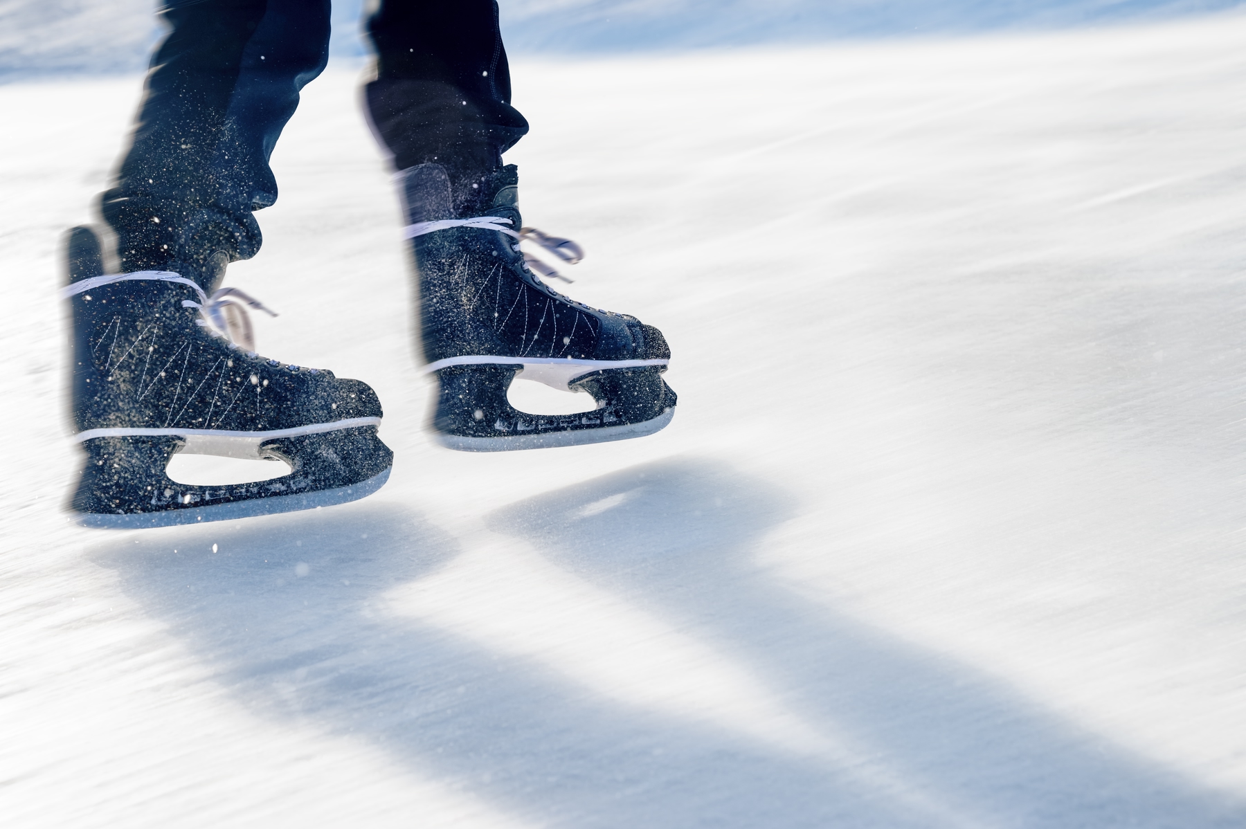 close up of feet wearing ice hockey skates, skating on an outdoor rink