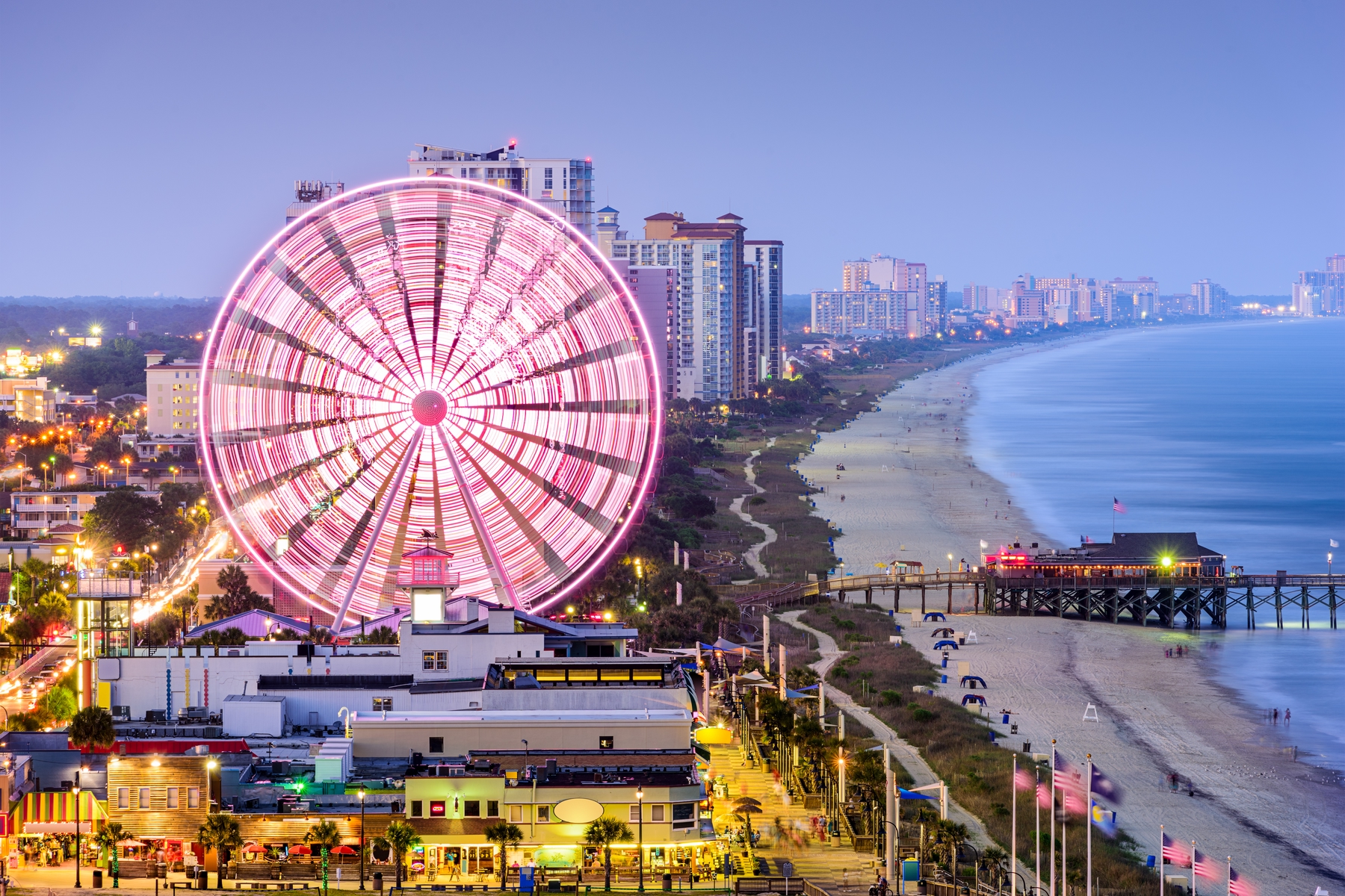 aerial view of Myrtle Beach in the evening, with the ferris wheel glowing in a bright pink