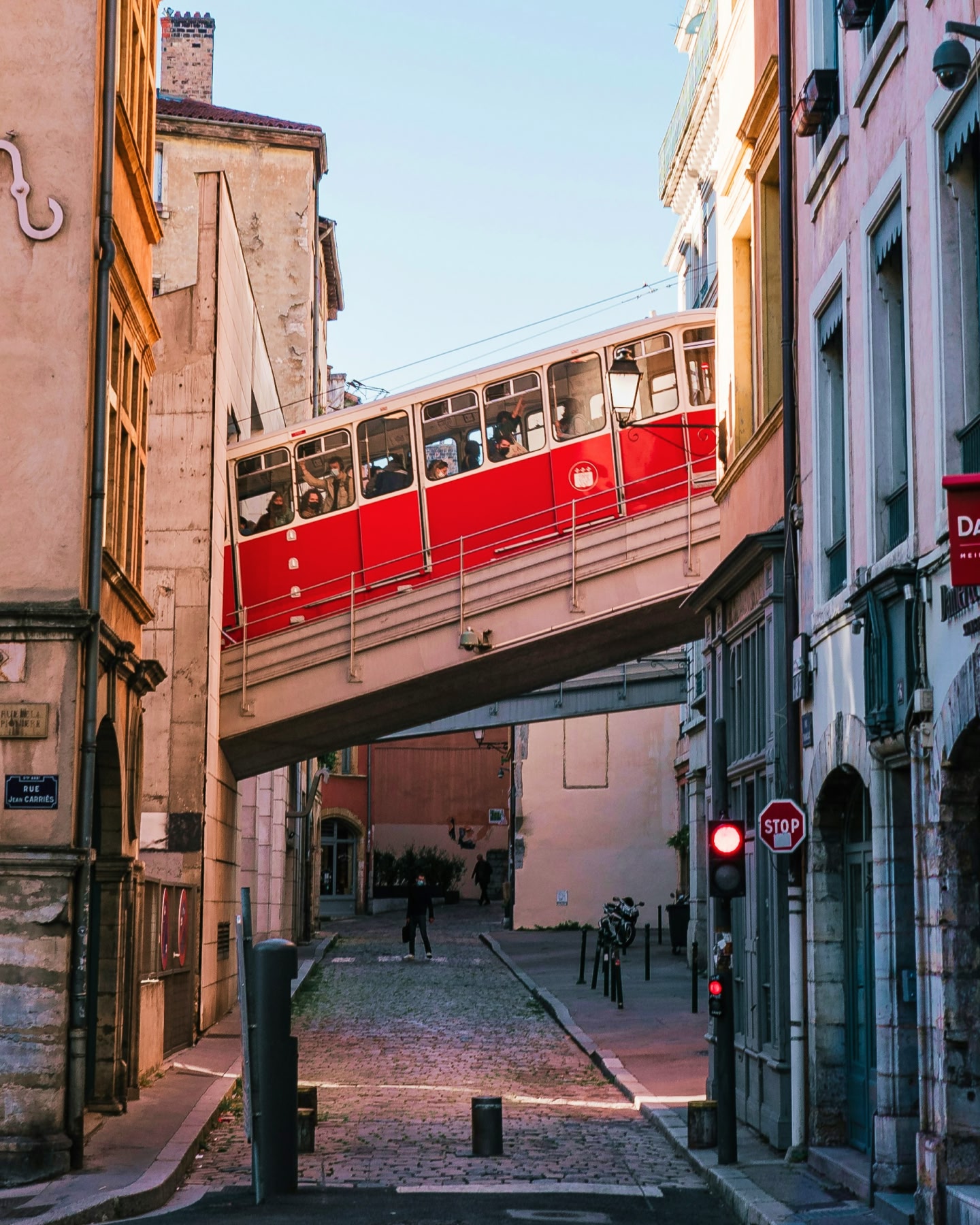 A red tram passes through a cobbled road in Lyon, France.