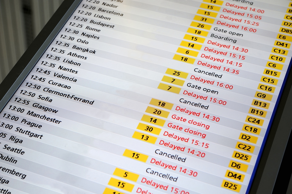 A flight status board with many flights delayed or cancelled