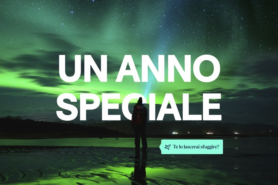 Persona che osserva l'aurora boreale sotto un cielo stellato verde. Testo al centro: “UN ANNO SPECIALE”. In basso a destra, un pulsante con icona aereo dice: “Te lo lascerai sfuggire?”.
