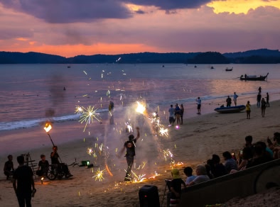 immagine di danzatori del fuoco sulla spiaggia con un tramonto