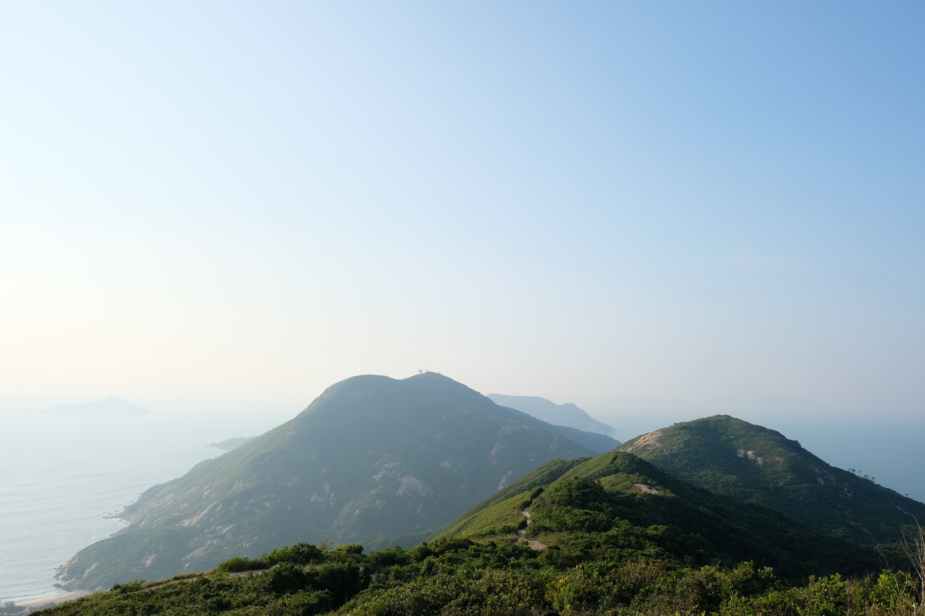 Peak of Dragon's Back hike in Kowloon, HK. Blue and foggy sky.
