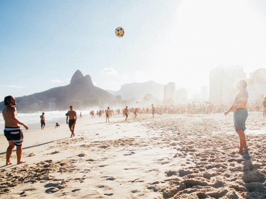 Pessoas jogando altinha na contra-luz na praia de Ipanema - para onde viajar gastando pouco