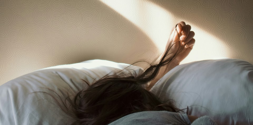 Woman untangling hair whilst in bed