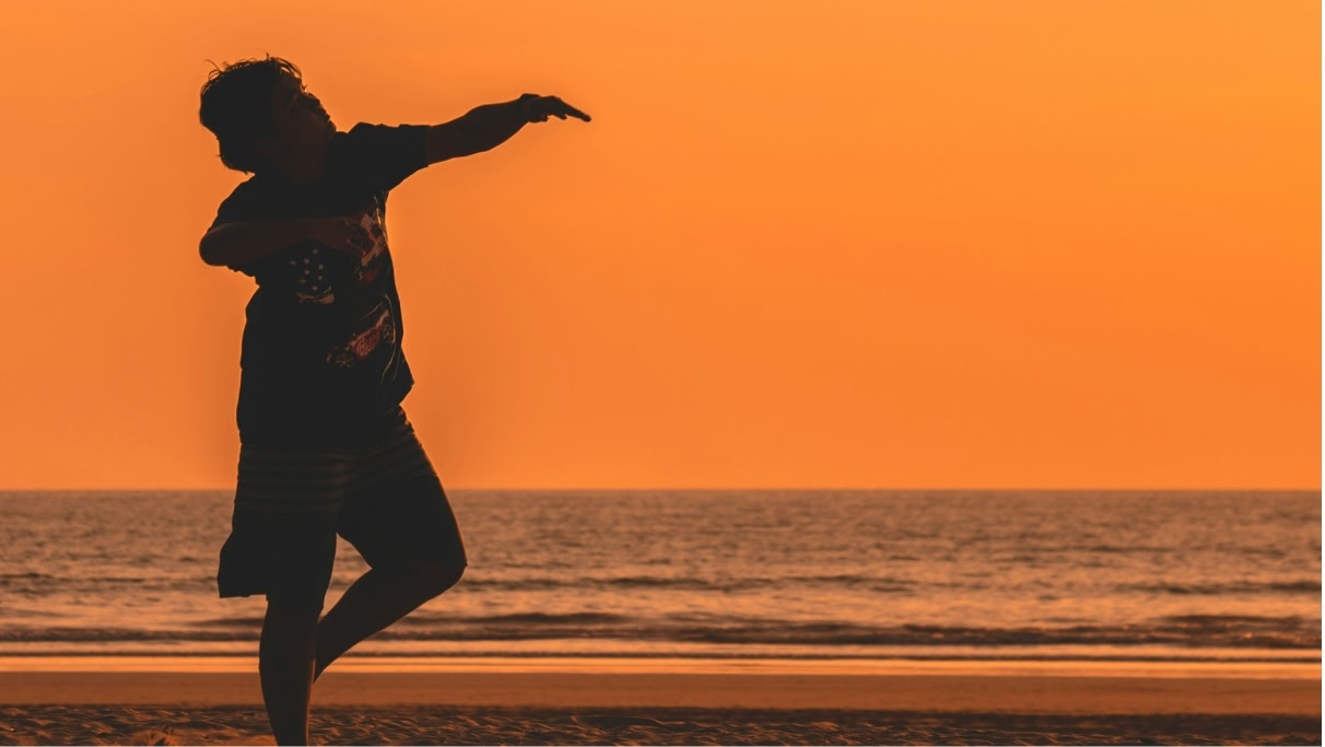 person's silhouette dancing by the sea during sunset time 