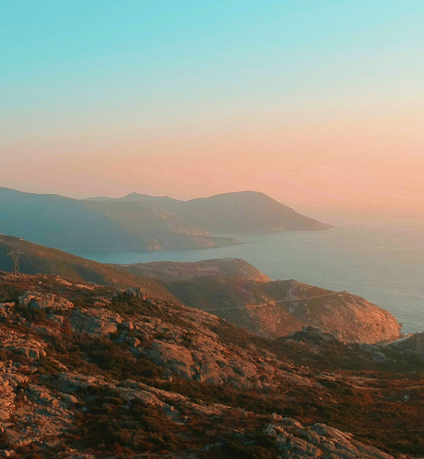 Goldenes Licht überzieht die felsigen Klippen und das ruhige Meer in der Abenddämmerung nahe Calvi auf der Insel Korsika, Frankreich.