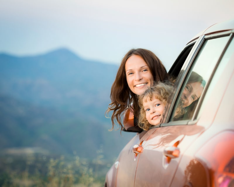 Mother and daughter popping their heads out of a car window