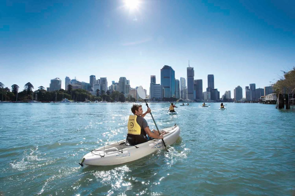 un homme fait du kayak devant un paysage urbain 