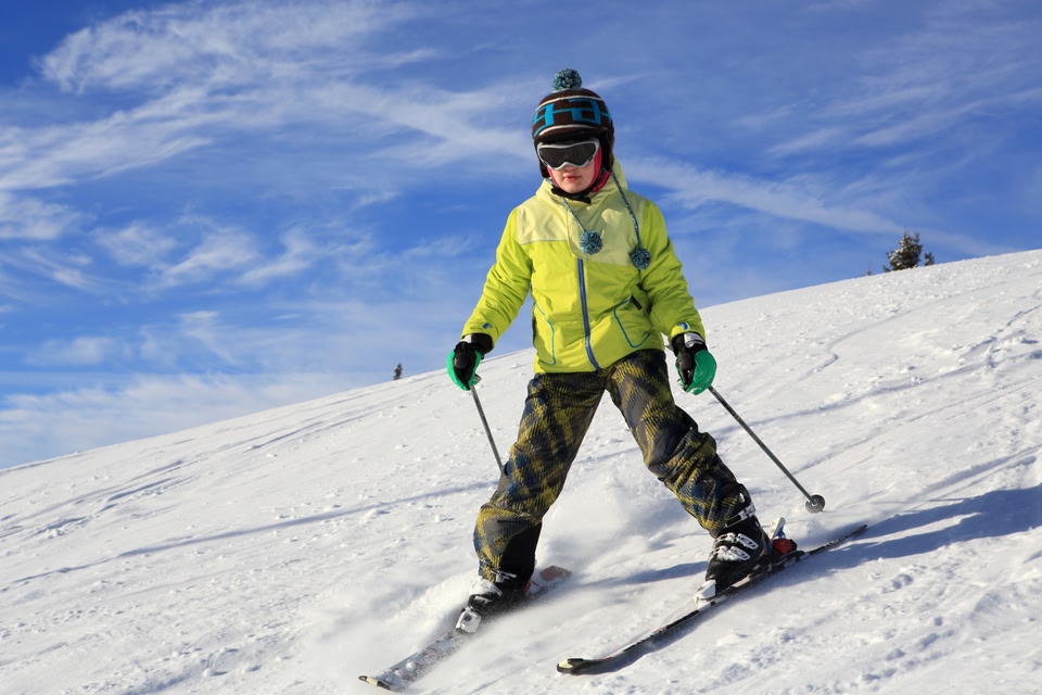 A person in brightly coloured ski clothes coming down a ski slope in Glencoe.