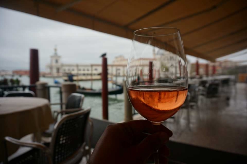 glass of wine overlooking a cafe by the canal in Venice, Italy
