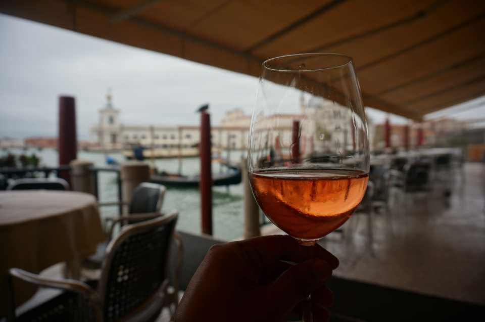 glass of wine overlooking a cafe by the canal in Venice, Italy