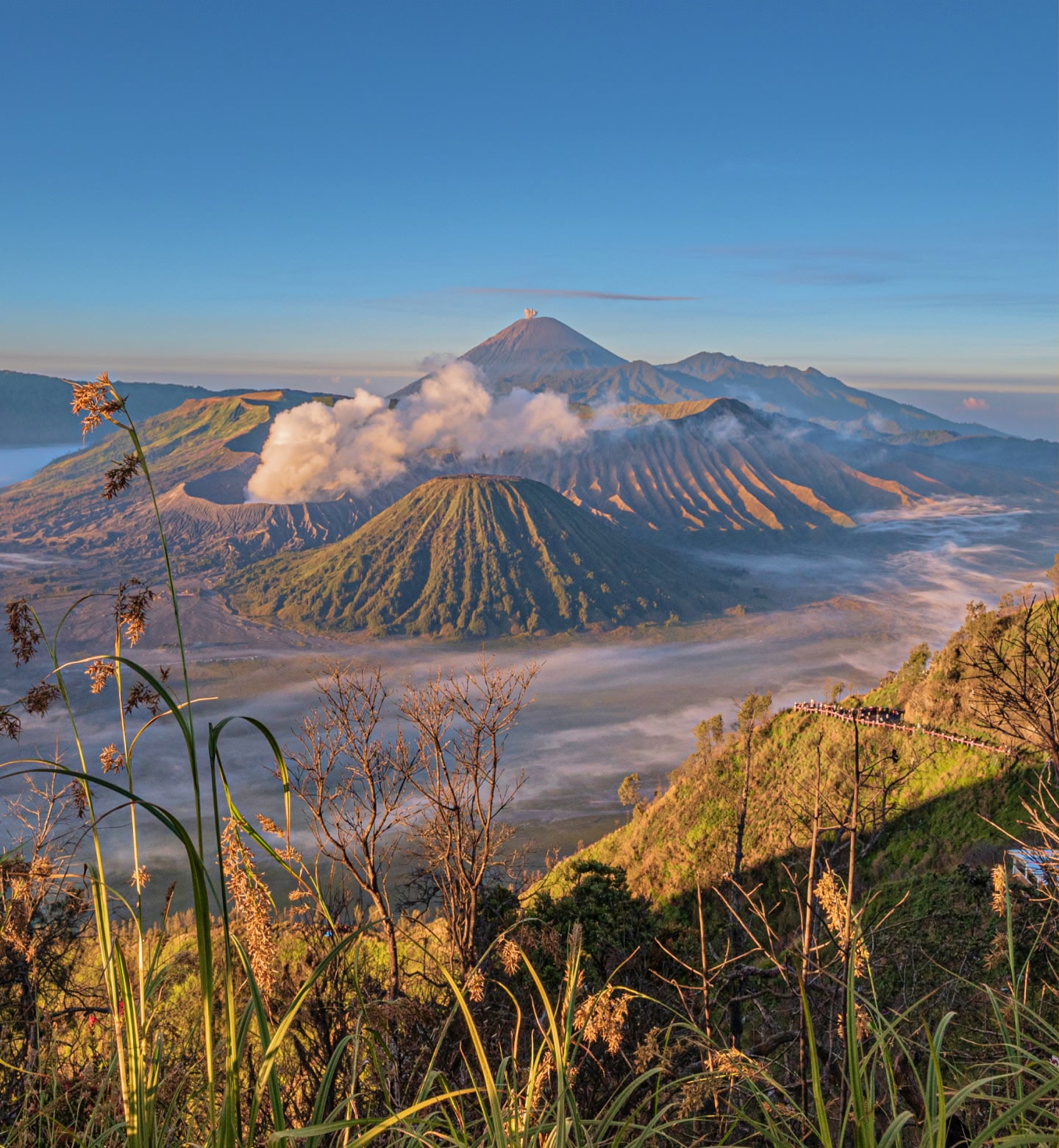 インドネシアのスラバヤ近郊、霧深い谷の上で噴煙を上げるブロモ山と近くの山々。