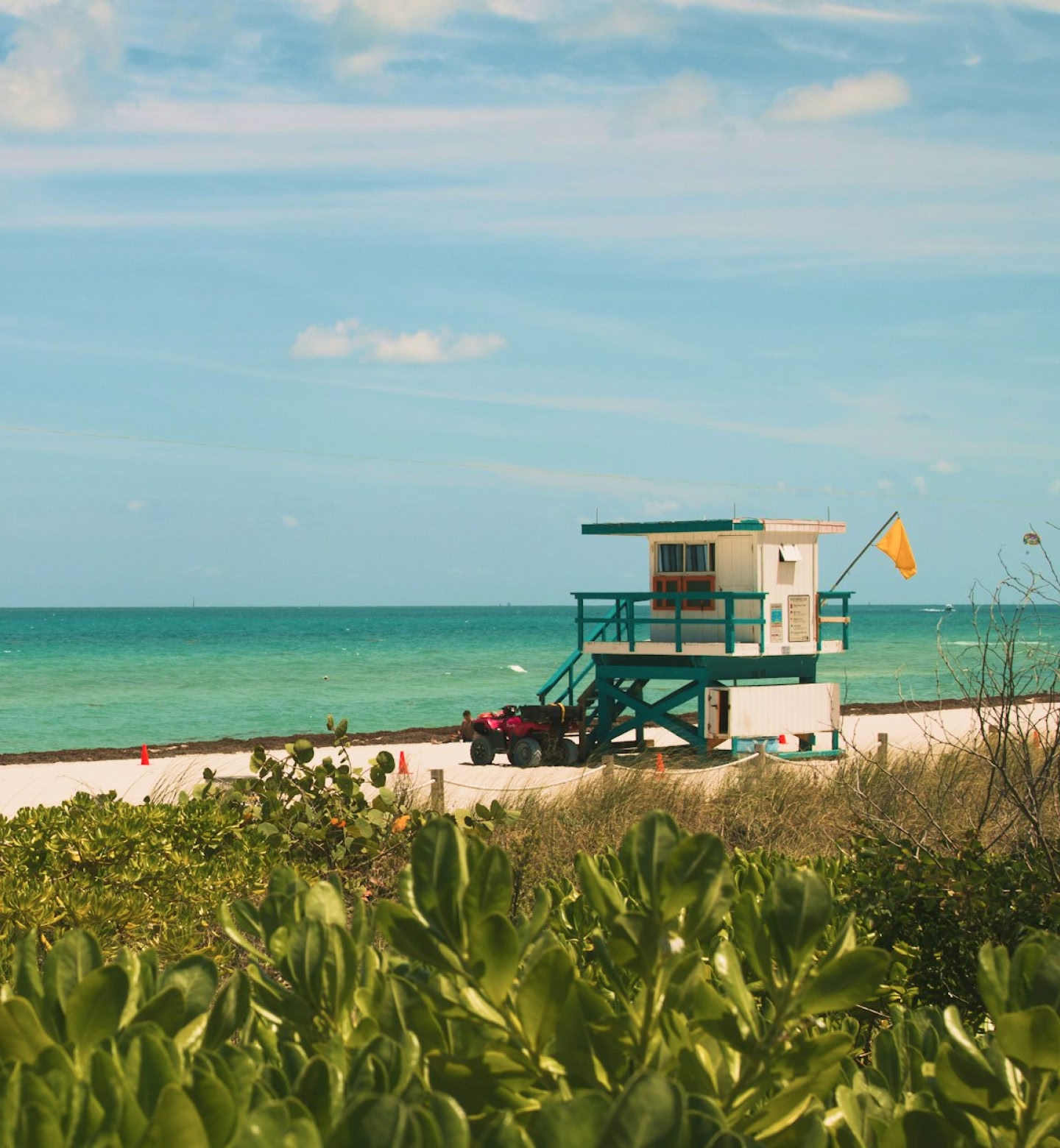 A lifeguard hut and yellow flag on a quiet, tropical beach in Miami.