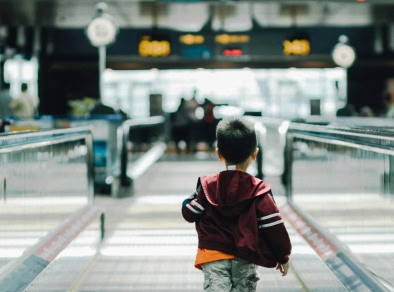 un ragazzino che corre su una scala mobile dell'aeroporto