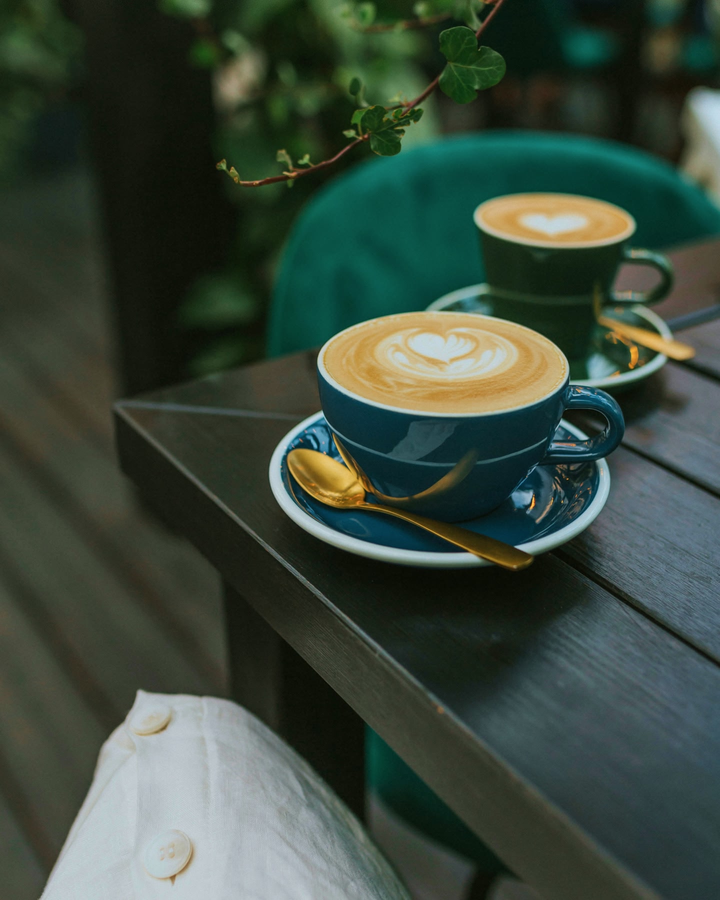 كوبان من القهوة تعلوهما رغوة على شكل قلب، ويقدمان في فنجانين أزرقين على طاولة.