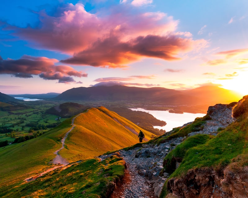 Sunrise on Catbells Mountain, The Lake District, Cumbria, England. Hiker walking along a path on the mountain ridge.