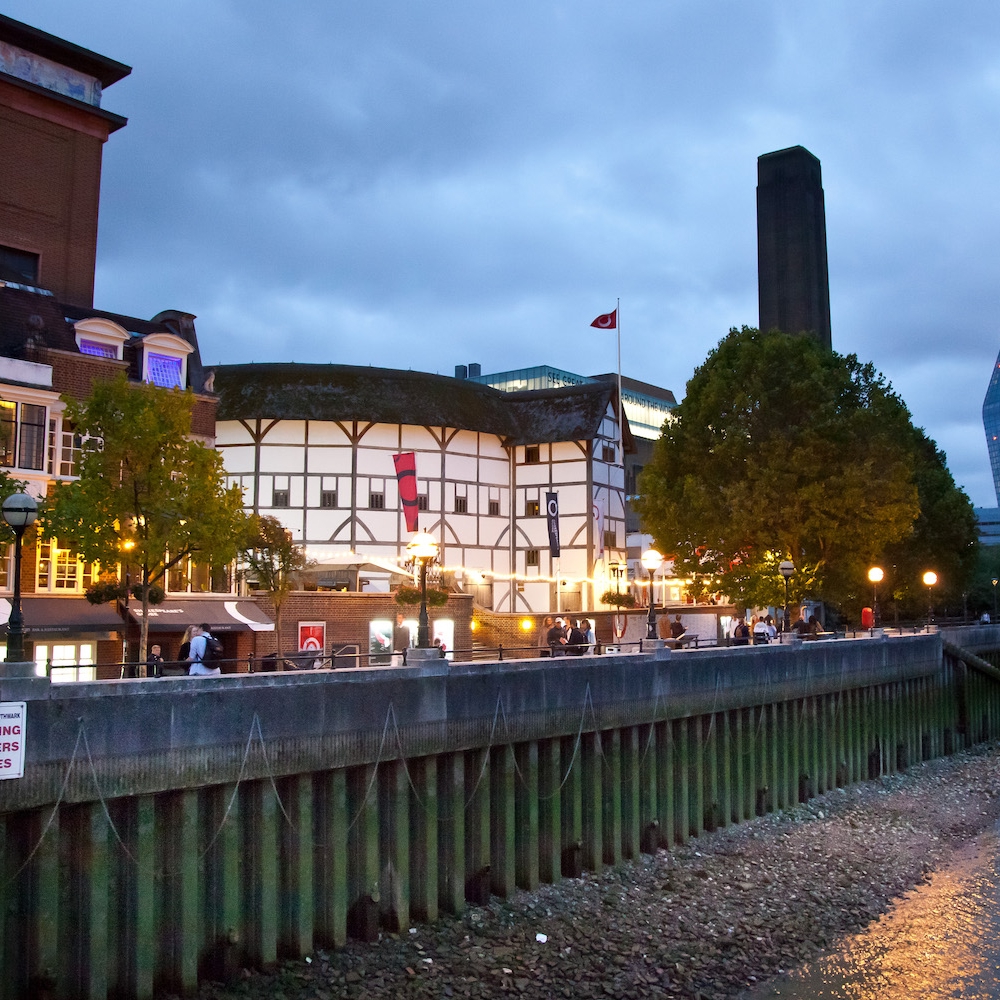 Shakespeare's Globe Theatre, a rounded, Elizabethan style building, viewed from across the river.