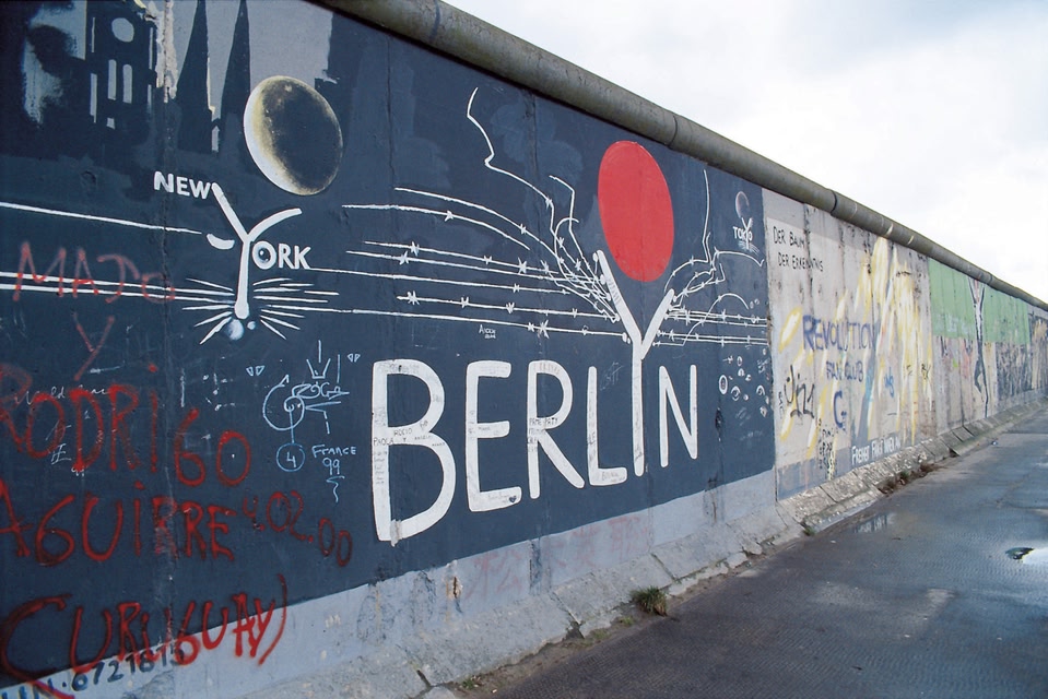 A section of the Berlin wall with some graffiti on it that says 'Berlin'