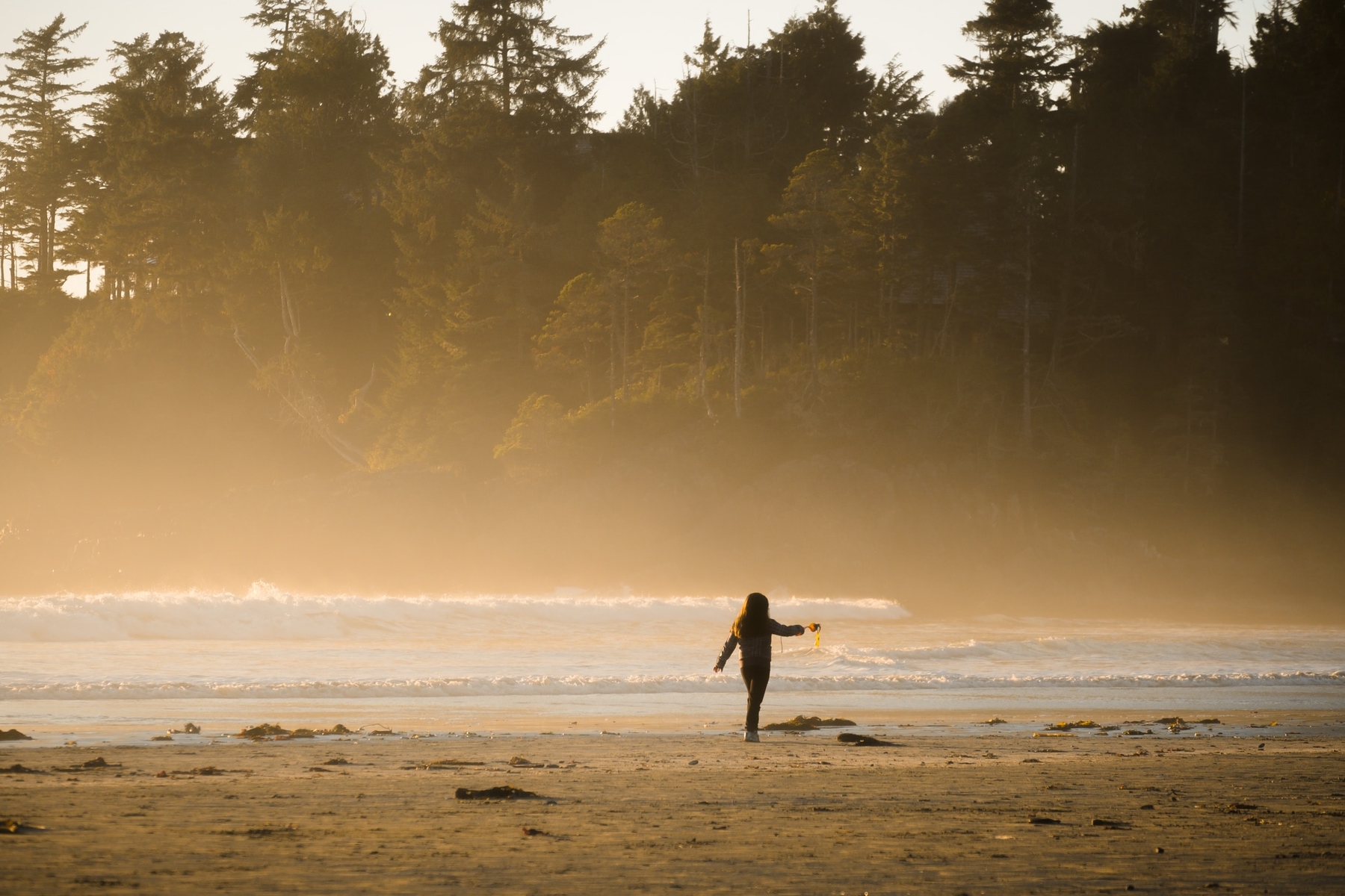girl walking along the beach in Tofino, BC on a misty day