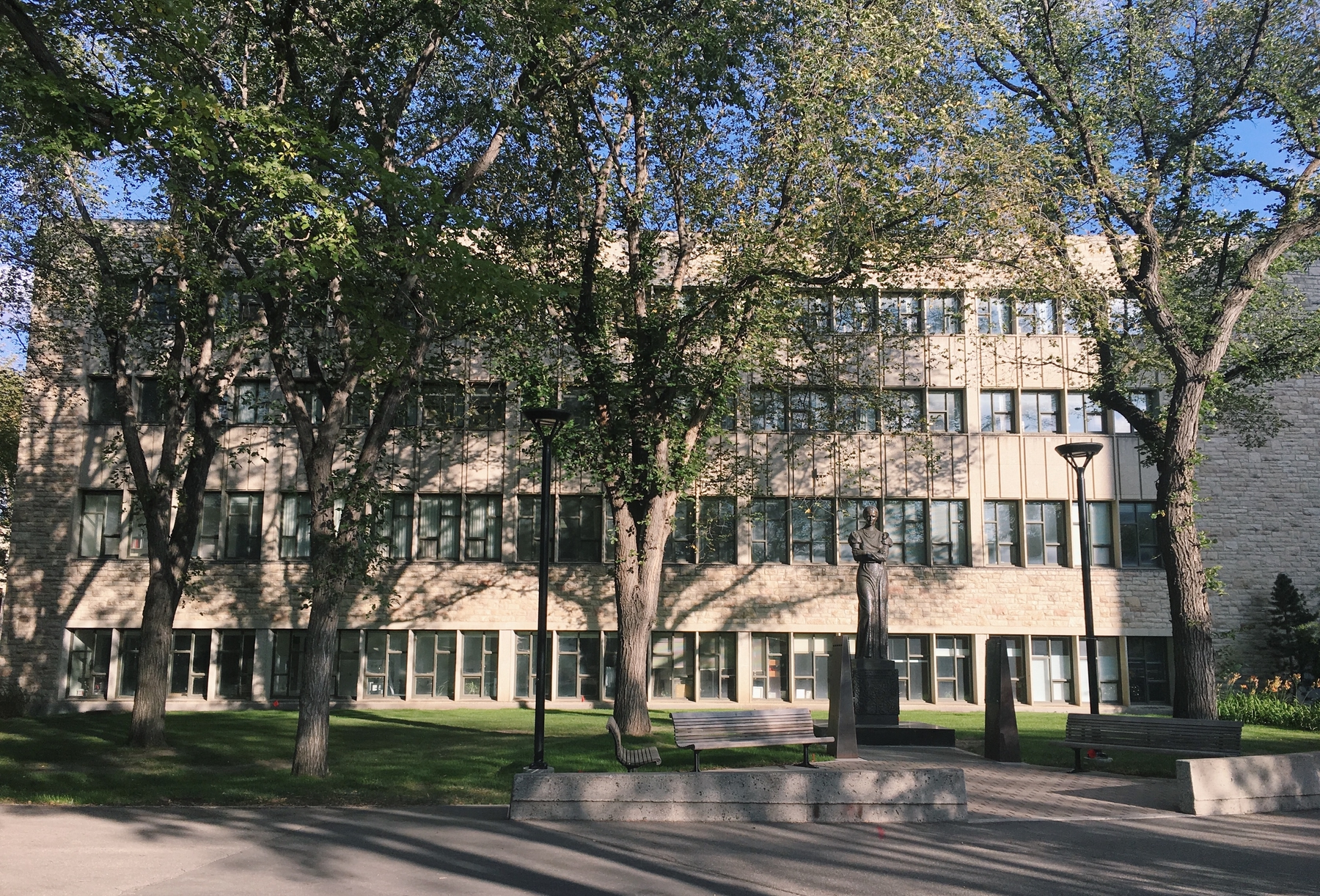 Building at the University of Saskatchewan in Saskatoon. grass and trees in front of building on a sunny day.