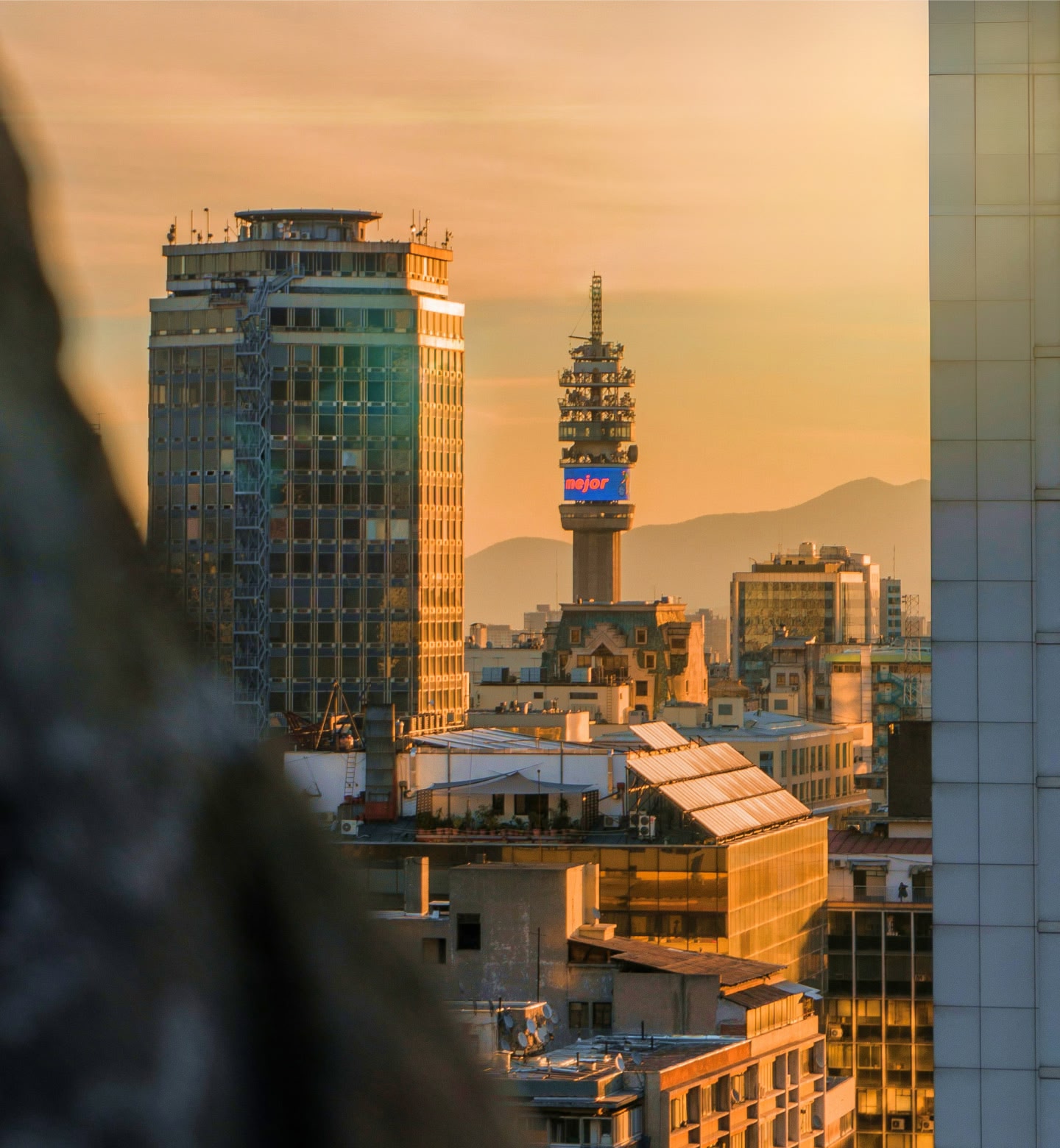 Uma luz dourada brilha atrás dos arranha-céus e das montanhas de Santiago.