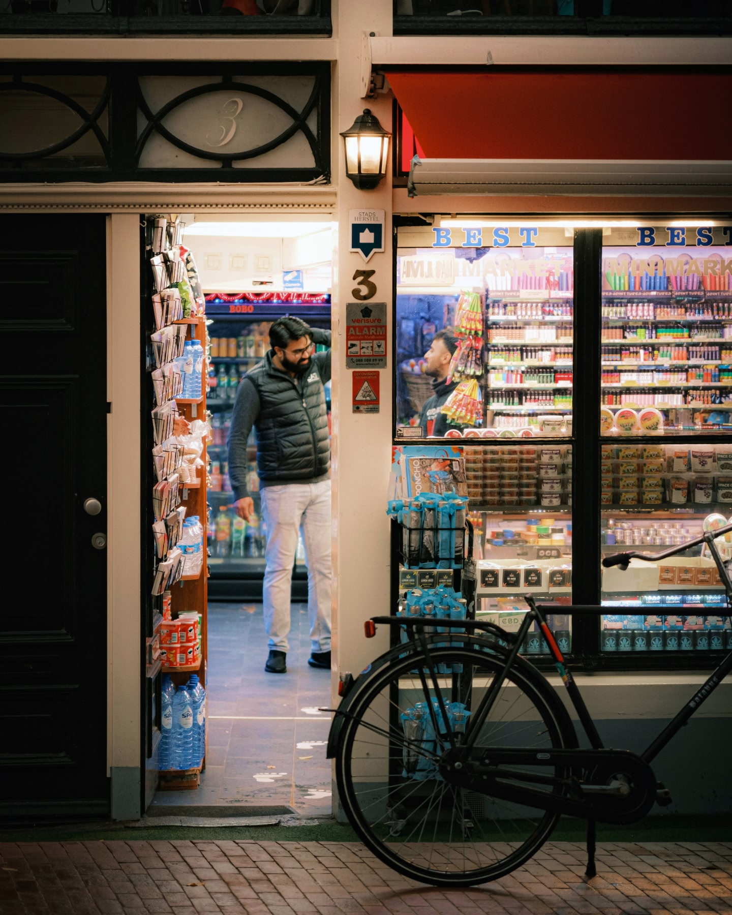 夜に、明るく照らされたコンビニで買い物をする男性。