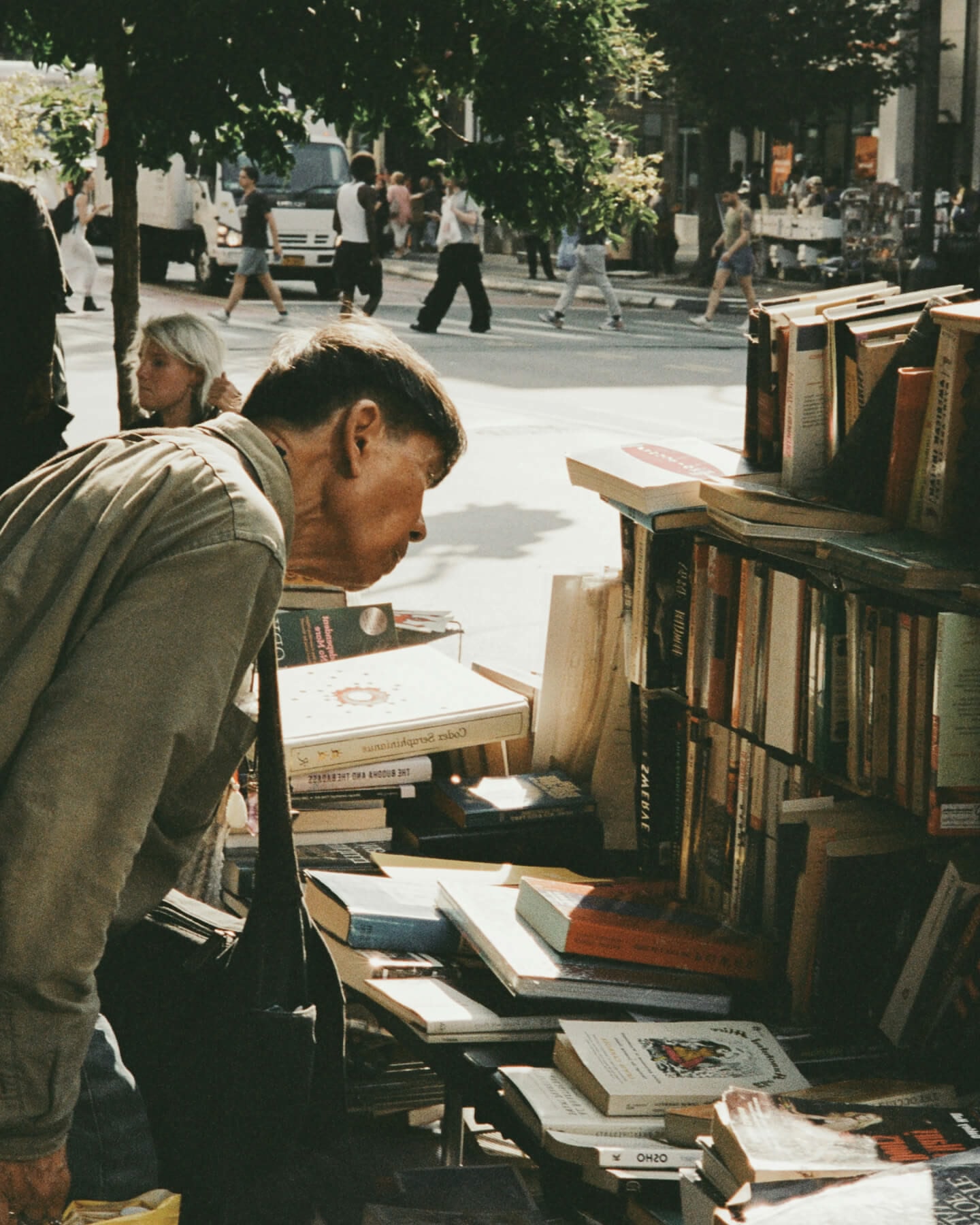 Un hombre con una chaqueta gris ojeando un puesto de libros en la calle