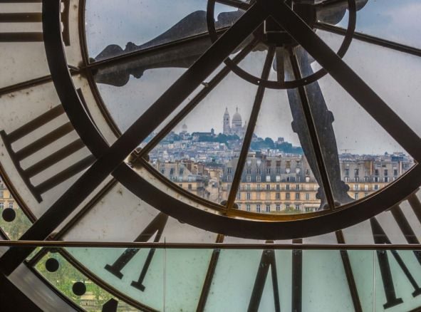 An artistic image of a large building with a clock with the view of the city from it.