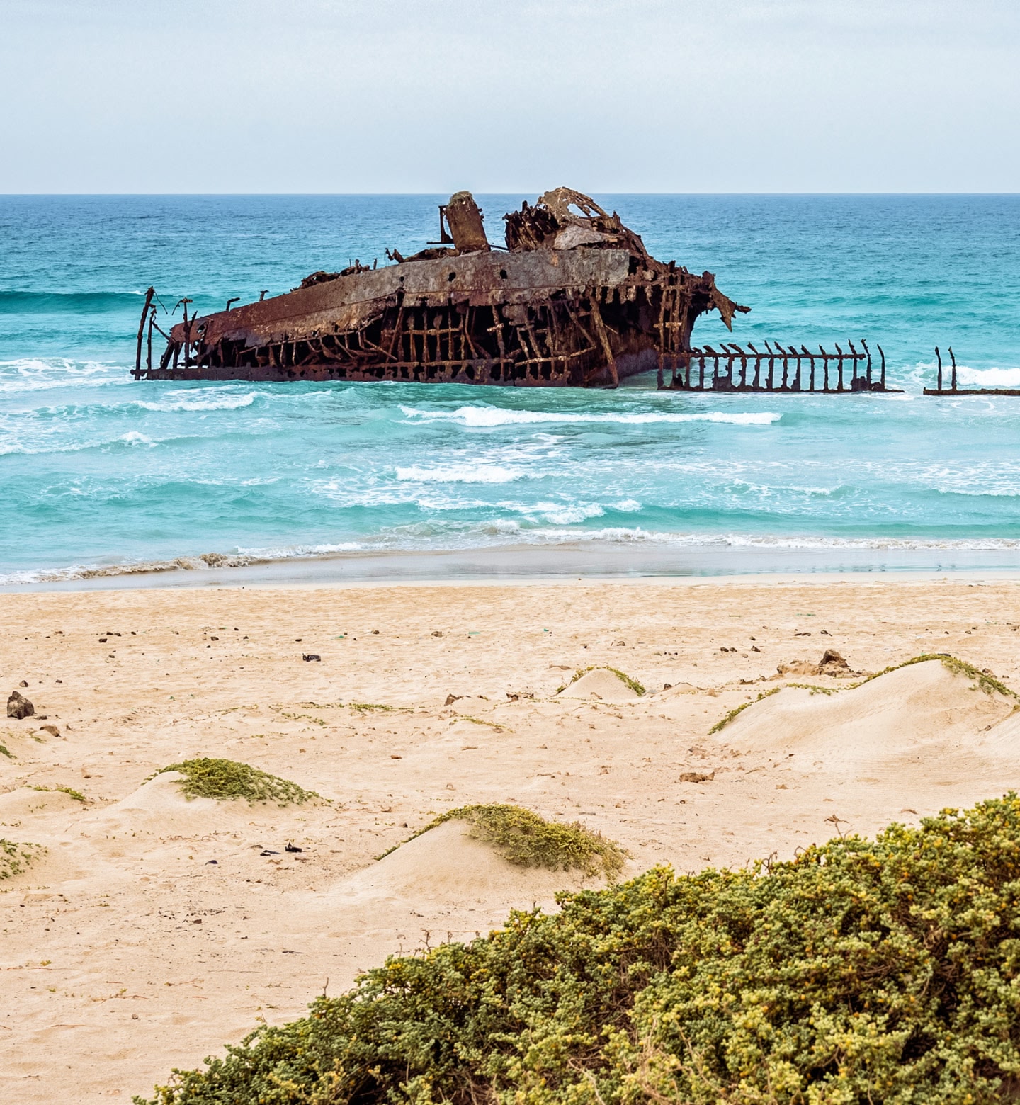 Une épave rouillée repose dans des eaux turquoise près d'une plage de sable à Praia, au Cap-Vert.