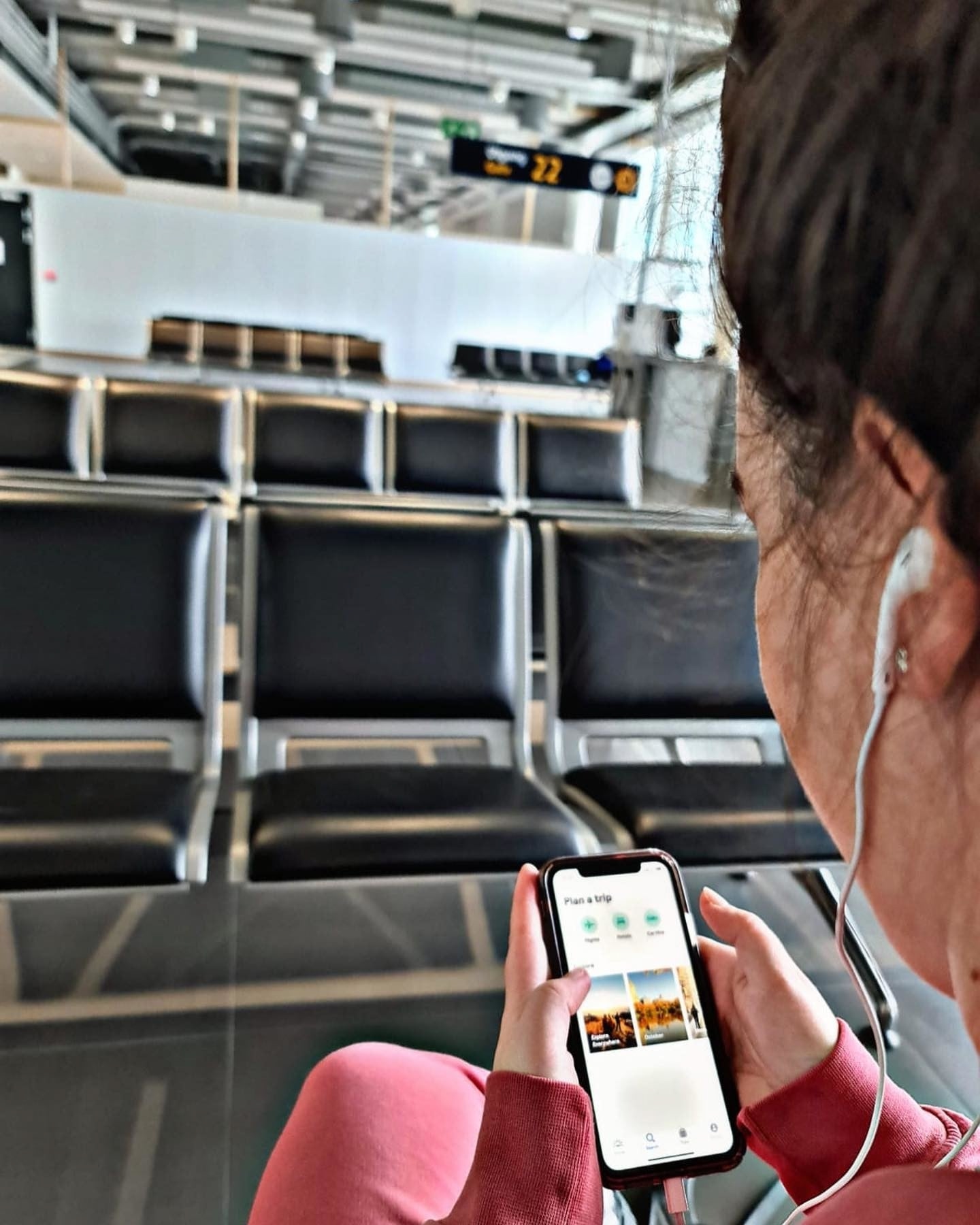 Frau wartet am Flughafen und schaut aufs Handy - Flughafen-Tipps