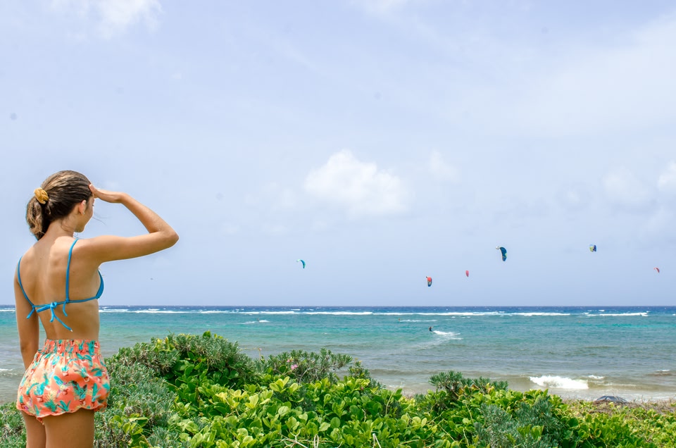 Frau blickt auf Strand mit Kitesurfern