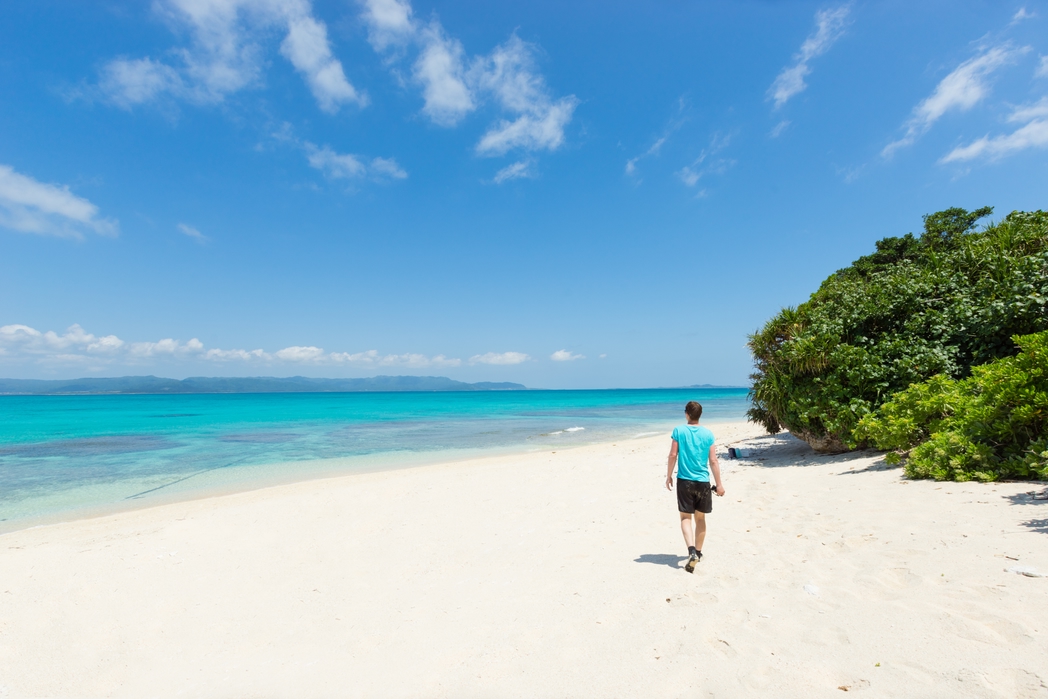 Man walking in tropical lagoon paradise of Okinawa - when is the best time to visit Japan
