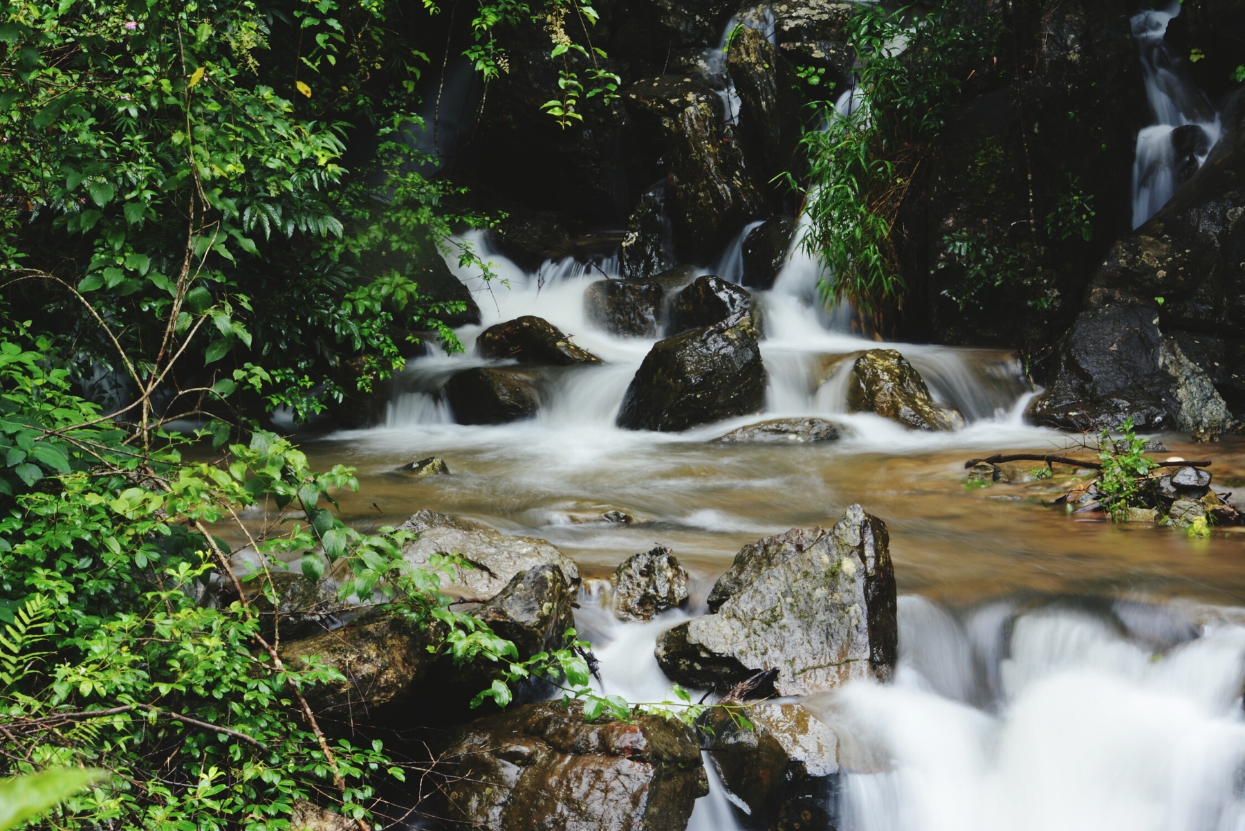 Long exposure of waterfall between rocks and leaves