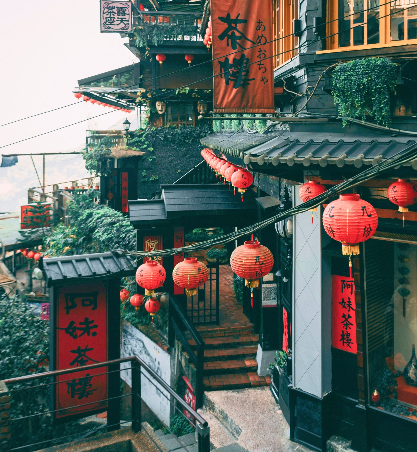 Red lanterns and signs hang outside a cluster of dark buildings on a hillside in Taipei, Taiwan.