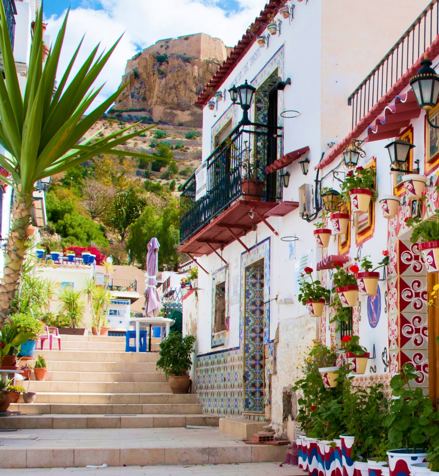 Weiß getünchte Straße in Alicante, Spanien, mit Blumentöpfen und bunten Akzenten