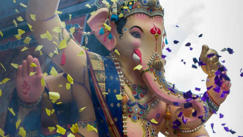 A vibrant and intricately designed Ganesha statue adorned with a multitude of colors, featuring the deity's iconic elephant head and multiple arms.