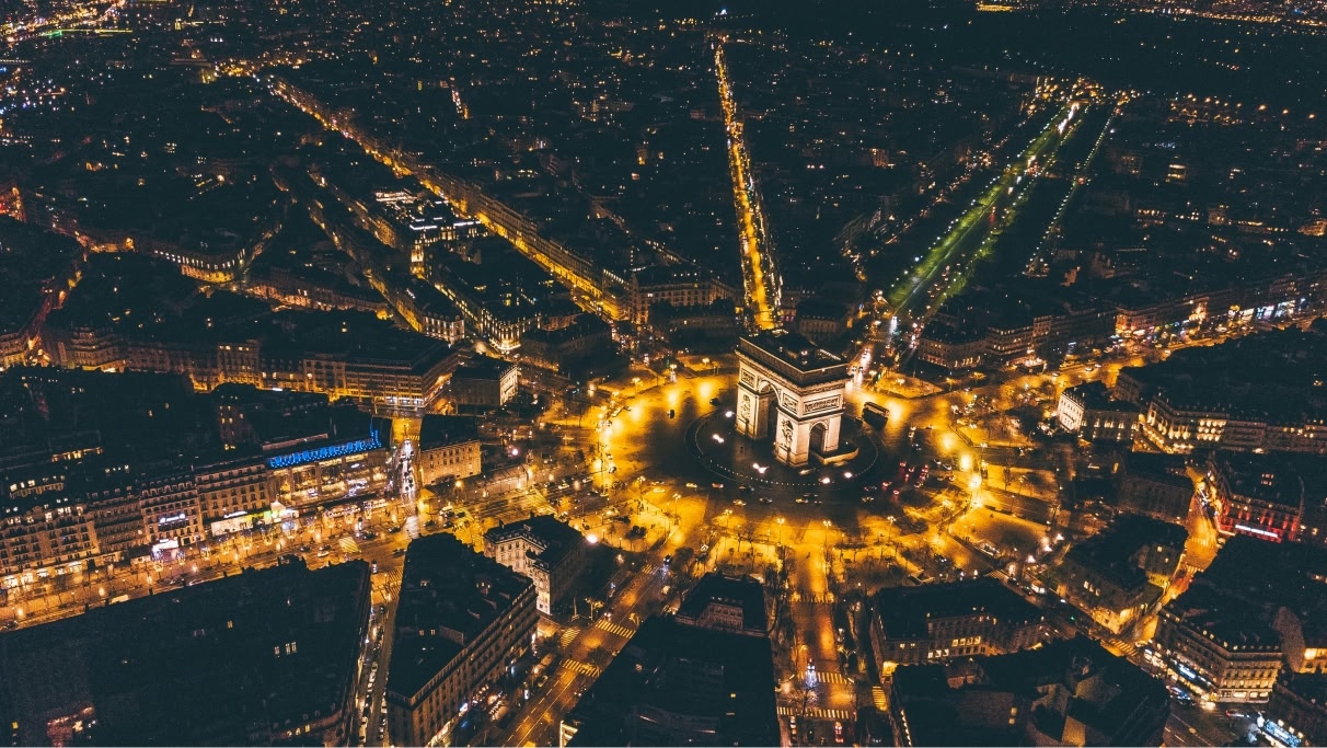 Arc de Triomphe in paris at night with yellow lights down the streets lit up by the cars 