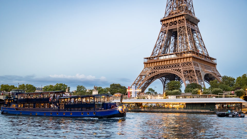   La Torre Eiffel vista dall'altra parte del fiume, con una nave da crociera in primo piano.