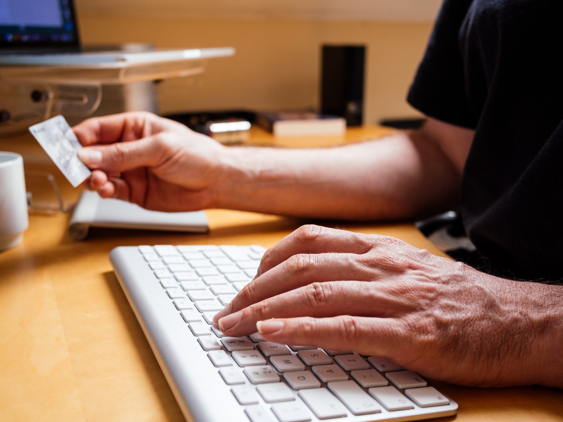 Man typing with credit card in hand