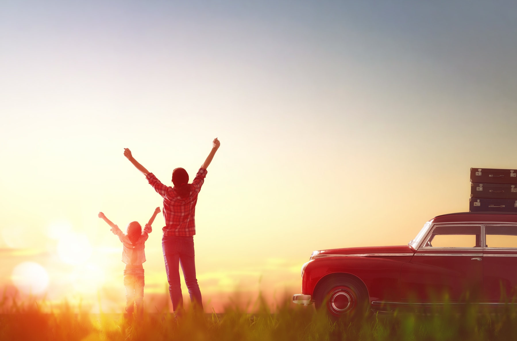 mom and daughter stretching outside of parked car looking at the sunset