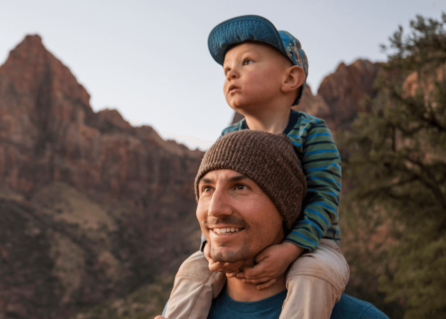 Child sitting on an adult's shoulders.