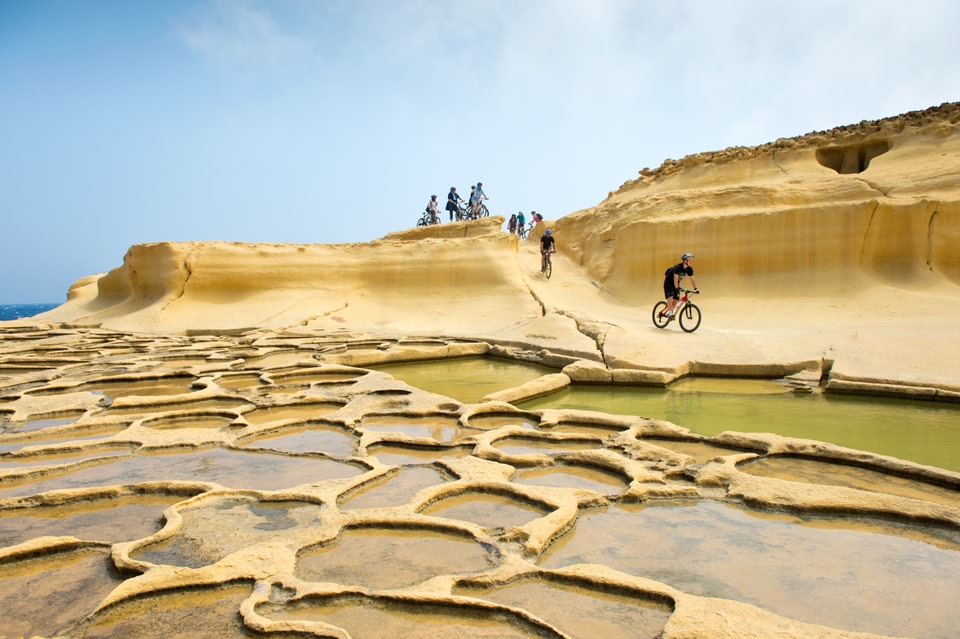 les bassins de sel et les gens en VTT à Gozo sous le soleil en avril