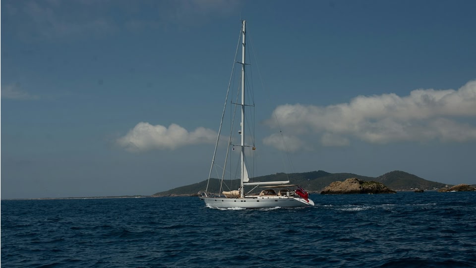 Barca a vela bianca su un mare blu sotto un cielo nuvoloso.