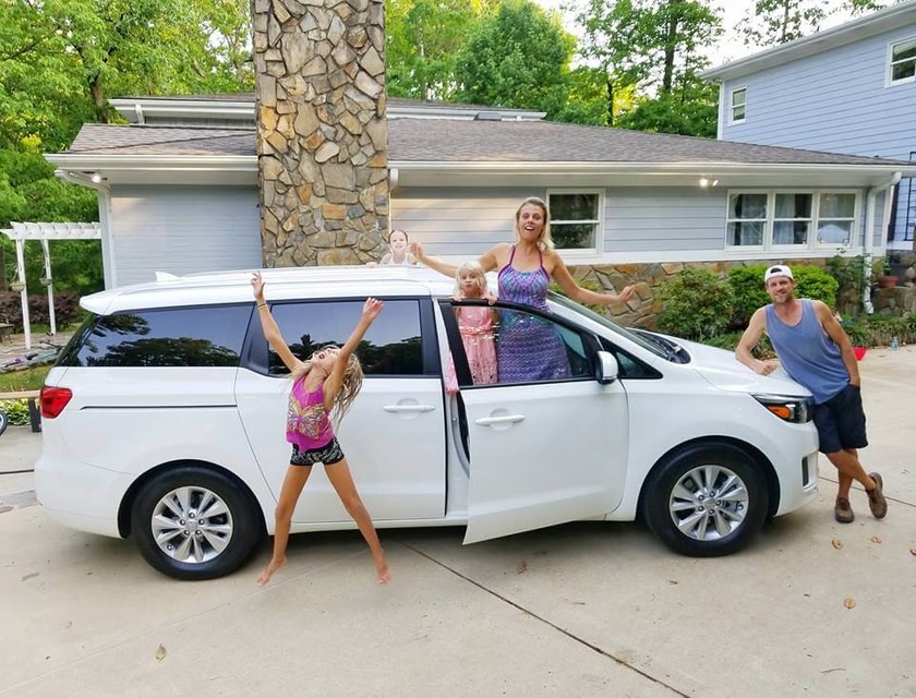 family standing outside of parked car excited for their road trip